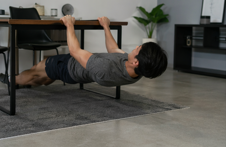 man doing inverted row using table at home